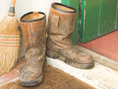 Work boots sitting on door step with broom