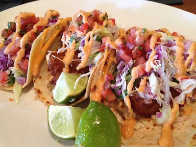 photo of 3 fish tacos on a plate with lime wedges