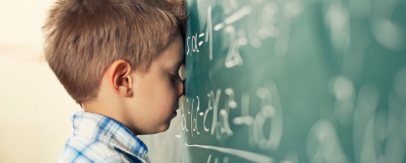 male child with nose against blackboard 